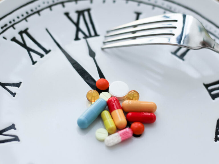 Hoop medicijnen op klok met wijzerstand 5 voor 12; een vork om medicatie op te eten. Hoog tijd om je medicijngebruik in vraag te stellen.