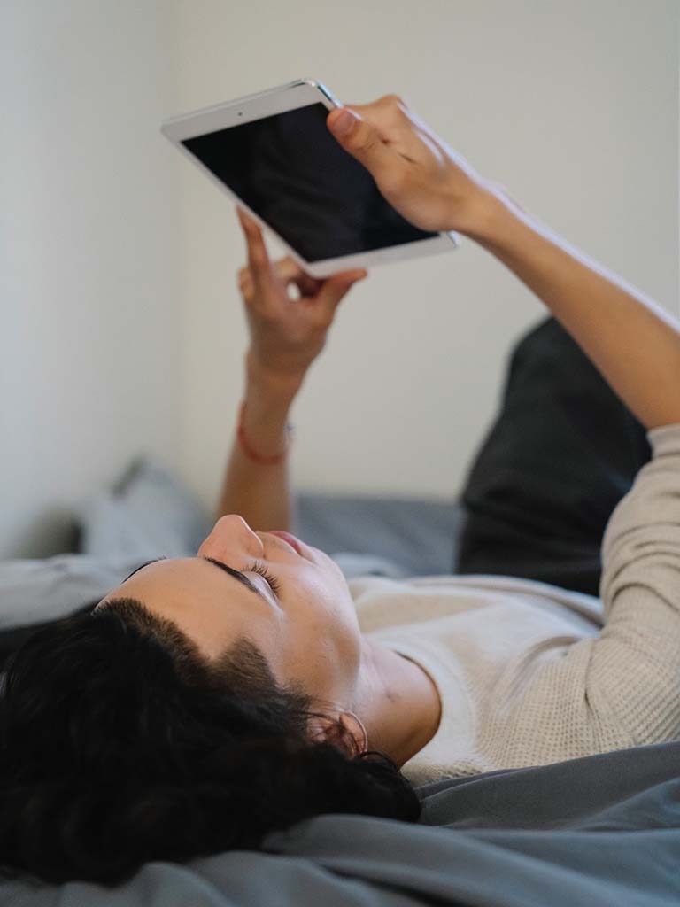 Man met pornoverslaving kijkt naar iPad in slaapkamer.