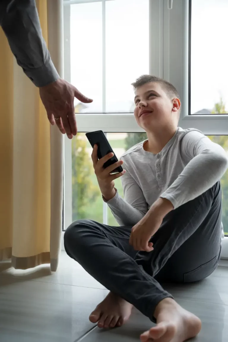 Vader steekt hand uit naar zoon met gsm verslaving om zijn smartphone af te geven.